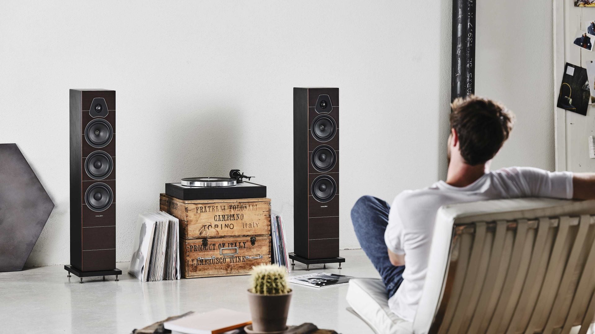Sonus faber Lumina III floorstanding speakers bookending a turntable, while a man on a couch revels in the immersive soundscape.