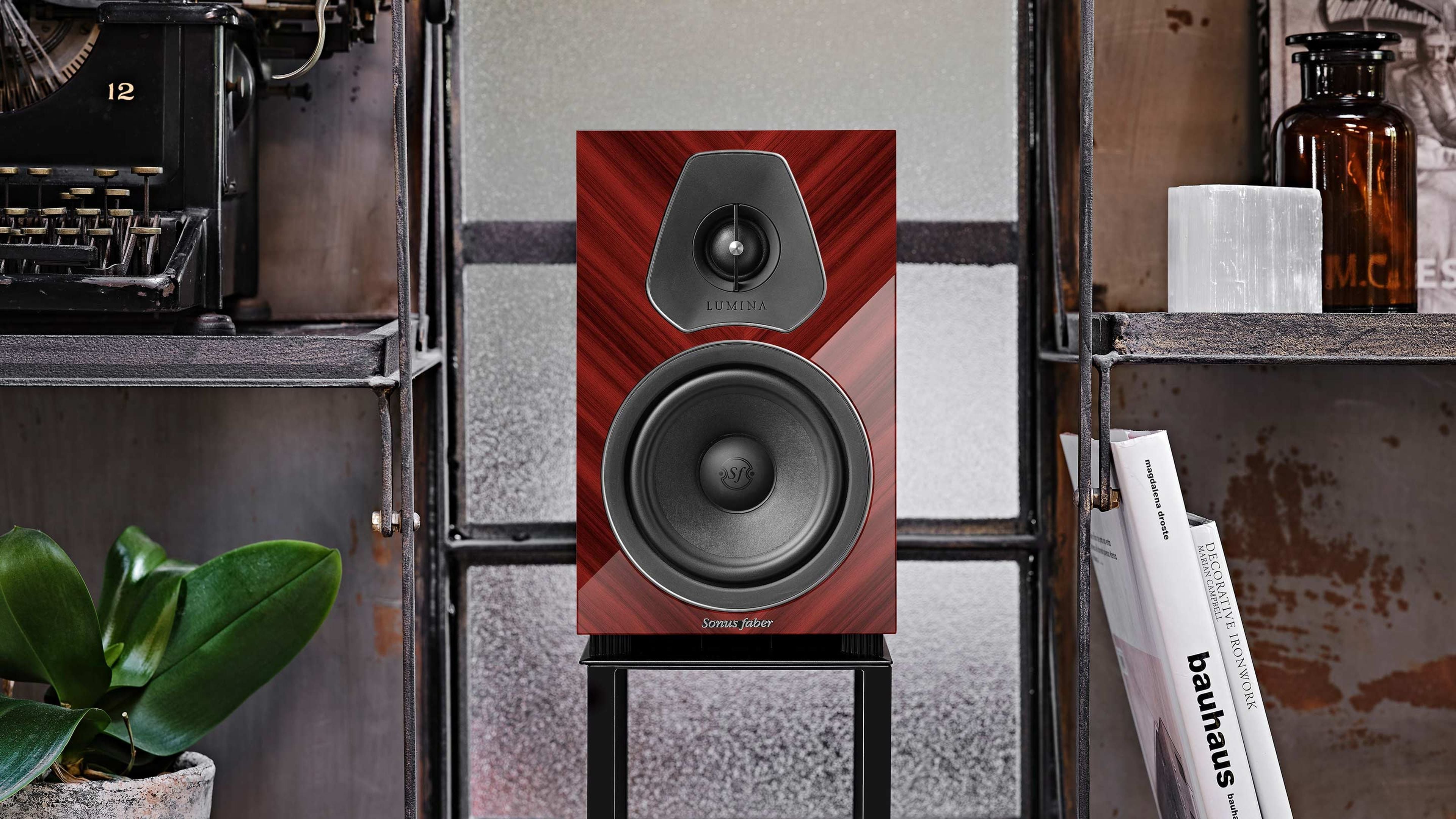 Un diffusore Sonus faber Lumina II Amator in legno multistrato rosso lucido con pelle nera in una sala audio domestica.
