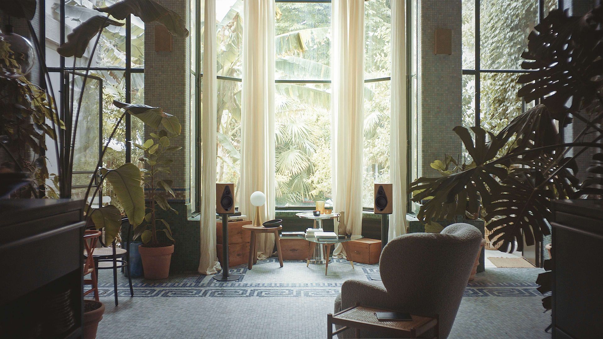 Invitante installazione domestica con una coppia di diffusori wireless Sonus faber Duetto su supporti, che creano un ambiente accogliente in mezzo a una vegetazione lussureggiante.