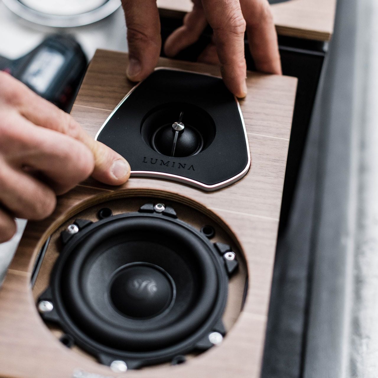 Un artesano italiano de Sonus faber coloca delicadamente el tweeter en un altavoz de estantería Lumina II, mostrando precisión