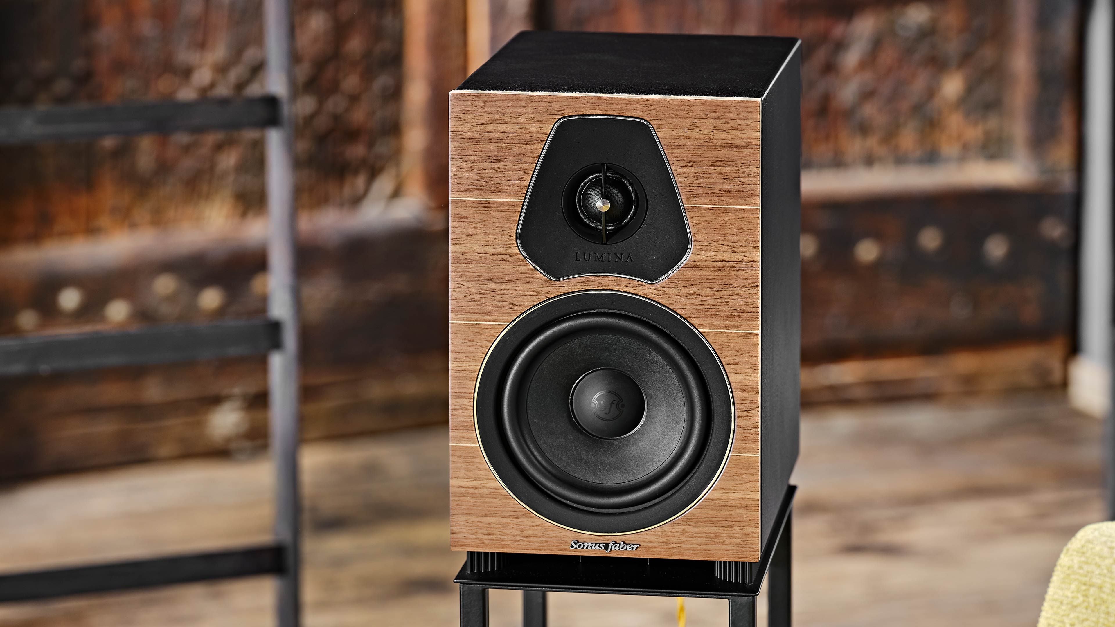 Primer plano detallado del altavoz de estantería Sonus faber Lumina II en nogal, incrustaciones de arce, madera multicapa y cuero negro.