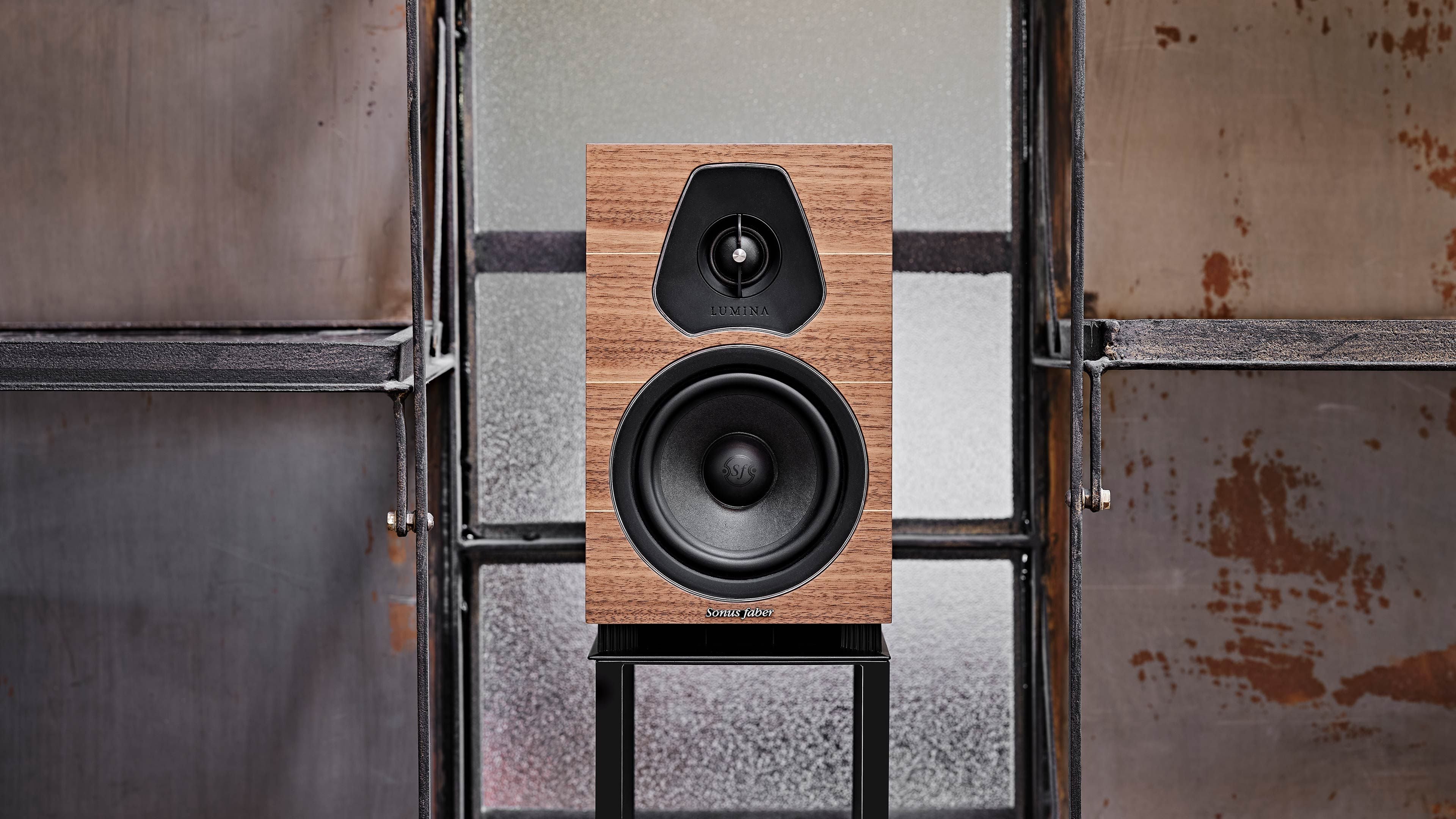 Altavoz de estantería Sonus faber Lumina II presentado elegantemente sobre un soporte, con madera de nogal y enfatizando los materiales naturales.